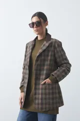 Blazer de corte relajado con estampado de cuadros tipo pied de poule en tonos rojizos y verdes. Presenta solapas clásicas en color azul oscuro y estructura definida.