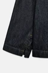 Chaqueta de denim azul oscuro con cuello solapa, manga larga y cierre frontal mediante alamares decorativos de estilo oriental.