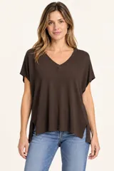 Remera de punto color marrón chocolate, con cuello en V, mangas cortas caídas y aberturas laterales en el dobladillo asimétrico, más largo en la parte trasera.