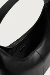 Bolso tipo shopper color negro con diseño liso, asa de hombro y compartimento principal con cierre de cremallera.