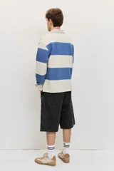 Chomba de friza de manga larga con diseño de rayas horizontales anchas en color beige y azul, cuello polo y pequeño bordado en el pecho.