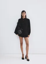 Blusa Lucy de diseño recto color negro, confeccionada en mezcla de algodón y viscosa. Cuenta con cuello mao, detalles bordados calados, manga larga y cierre frontal con botones.