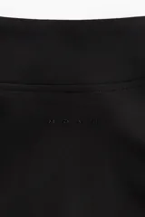 Campera deportiva corta de color negro con cierre frontal, cuello alto y mangas largas con abertura para el pulgar.