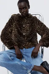 Campera de piel sintética con estampado de leopardo, cuello redondo y cierre frontal con botones. Presenta un diseño de corte recto y forro interior.