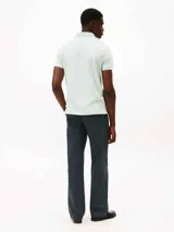 Chomba celeste de Tommy Hilfiger, modelo 1985, de corte regular, con cuello tipo chomba, cartera de dos botones, logo de Tommy Hilfiger bordado en el pecho y mangas cortas.