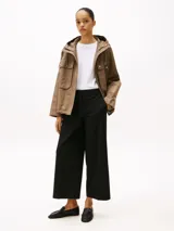 Pantalón negro de corte amplio, tobillero y talle bajo. Confeccionado en tejido antiarrugas de mezcla de viscosa elástica. Presenta cierre de cremallera con enganche oculto, raya marcada en la parte delantera y trasera, y dos bolsillos traseros de ojal.