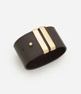 Pulsera ancha de material sintético color marrón oscuro, con diseño de cinta larga y dos tiras metálicas doradas aplicadas en el centro. Cuenta con un cierre de pino ajustable.