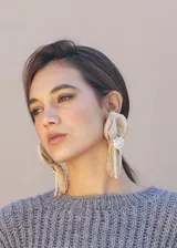 Aros colgantes con diseño de flor en rafia color beige, decorados con una pieza central de strass y flecos de hilo y cristales colgantes.