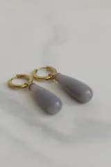 Aros tipo argolla con dije colgante en forma de gota de piedra natural en tonos marrones. Fabricados en acero quirúrgico dorado.