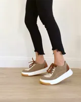 Championes de cuero color visón con cordones marrones, suela blanca y base color caramelo.