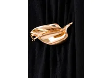 Vestido largo negro de punto con cuello alto, manga larga y detalle de aplique metálico dorado en la cintura.
