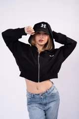 Campera cropped de estilo deportivo con cierre frontal completo, capucha y puños elásticos. Confeccionada en tela con frizza, presenta un diseño holgado y minimalista en color negro.