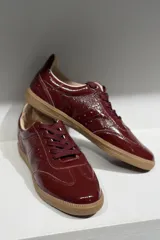 Championes de cuero vacuno con acabado brillante tipo charol, color azul marino, con cordones al tono y suela de goma color caramelo.