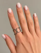 Anillo de acero plateado con diseño abierto y formas circulares entrelazadas.