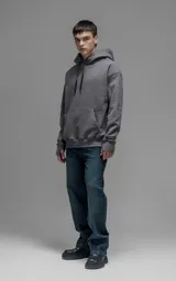 Hoodie oversize color gris oscuro, confeccionado en frisa premium con textura gamuzada. Presenta capucha ajustable con cordones personalizados, bolsillo frontal tipo canguro y puños con abertura para el pulgar.