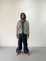 Campera reversible con cierre frontal. Un lado confeccionado en algodón azul marino con estampa plastisol, bordados con apliques y capucha. El otro lado presenta un diseño de polar de pelo largo en color gris. Posee corte oversize, puños y ruedo acanalados.