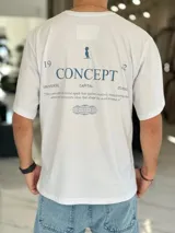 Remera oversize blanca de manga corta, con estampa en la espalda con la inscripción "Concept", un gráfico de pingüino con galera y esferas de líneas.