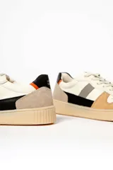 Zapatillas deportivas color beige con detalles en gris, blanco, negro y rojo.