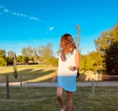 Vestido corto tejido en hilo de algodón color celeste, con cuello y espalda con apliques de cuero artesanal en tonos marrón, blanco y celeste.