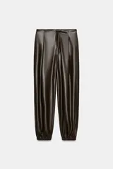 Pantalón jogger de tiro medio confeccionado en tejido efecto piel. Presenta pliegues en el delantero, bolsillos laterales, falsos bolsillos de vivo en la parte posterior y bajo acabado en elástico. Cierre frontal con cremallera, botón interior y gancho metálico.