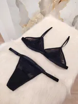 Conjunto de lencería compuesto por un corpiño triangular de microtul transparente con detalles de encaje en las copas y una tanga regulable con elástico ancho.
