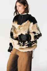 Buzo de peluche con estampado de paisaje montañoso en tonos beige, negro y blanco. Presenta cuello alto con cierre frontal, mangas largas con puños tejidos acanalados y corte holgado.