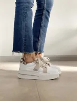 Sneakers de mujer estilo deportivo y urbano, color negro con detalles en beige claro. Presentan puntera y talón en negro, cuerpo principal en negro, y estrella lateral, cordones y tira de velcro en beige claro. La suela es blanca y el interior negro con la inscripción "LUCY IN THE SKY".