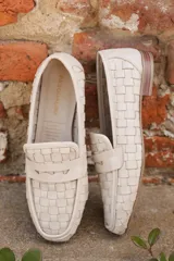 Mocasines de cuero napa color crema con diseño entrelazado, punta semicuidada, capellada estructurada con antifaz y suela plana con pequeño tacón.