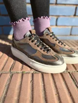 Zapatillas deportivas de cuero color peltre, con cordones negros y suela de goma blanca.