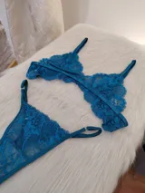 Conjunto de lencería de encaje floral color verde petróleo, compuesto por un corpiño triangular sin aro y una bombacha tipo colaless con tiras laterales ajustables.