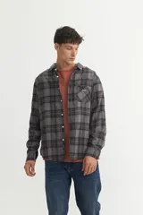 Camisa de franela a cuadros marrones y verdes, corte regular fit, confeccionada en algodón. Tiene cuello solapa clásico, bolsillo en el pecho y botones personalizados.