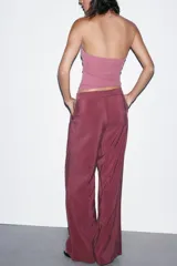 Pantalón de tiro alto color bordó, de corte ancho y pierna recta, con pinzas frontales y lazada ajustable en la cintura. El tejido presenta un acabado satinado o ligeramente arrugado.