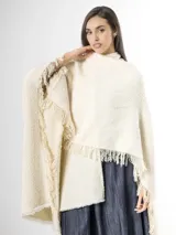 Ruana confeccionada en tejido de punto color off white, con diseño amplio y flecos en los bordes.