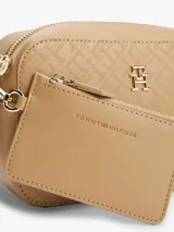 Bandolera Tommy Hilfiger color beige con monograma TH en relieve, cierre de cremallera, correa de cadena dorada extraíble y ajustable, bolsillo interior con cremallera, monedero extraíble con cremallera y logo TH dorado en el frente.