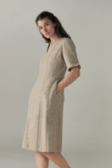 Vestido a la rodilla color beige, con escote en V, mangas 3/4 y bolsillos laterales.