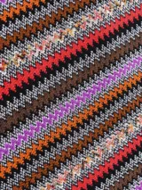 Chal tipo bufanda de lana, con diseño de zigzag vertical en múltiples colores vibrantes como marrón, negro, rojo, naranja y violeta. Presenta flecos en los bordes.