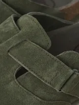 Zueco de gamuza verde militar con puntera redonda, tira ajustable con hebilla lateral, plantilla anatómica de corcho y suela de goma.