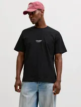 Remera negra de manga corta con cuello redondo y calce relajado, confeccionada en jersey de algodón orgánico. Presenta un pequeño estampado tipográfico en el centro del pecho con el texto 'JJ Studios'.