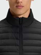 Chaleco acolchado de diseño técnico, con cierre frontal completo y cuello alto. Presenta un acabado liso y minimalista, ideal para capas intermedias o exteriores.