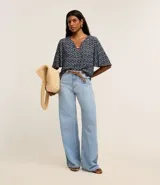 Blusa tipo bata de mangas cortas, confeccionada en viscosa con estampado de follaje en blanco sobre fondo azul marino. Tiene escote en V con detalle de abalorio en el centro.