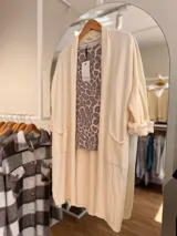 Saco largo abierto de tejido de punto color crema, con bolsillos delanteros y mangas largas. Diseño versátil y cómodo de corte holgado.