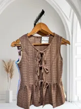 Blusa sin mangas de encaje con detalle de lazo en el escote y corte peplum.