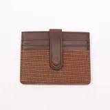 Tarjetero de cuero color marrón chocolate con diseño tejido en la parte inferior y cierre con broche a presión.