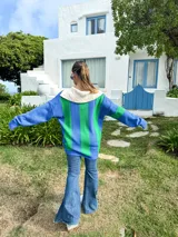 Sweater de punto azul con cuello polo blanco, diseño geométrico en el pecho en blanco y verde, y mangas largas.