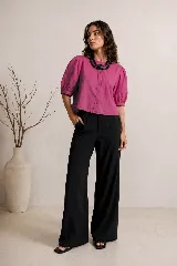 Blusa de color fucsia con mangas cortas abullonadas, cuello redondo y cierre frontal con botones ocultos de nácar.