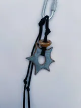 Charm para bolso o accesorios con mosquetón metálico, tejido de macramé en cordón negro y dijes de cerámica esmaltada en tonos violeta y celeste.