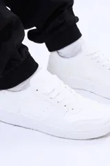Championes urbanos de diseño minimalista en color blanco, con cordones al tono y suela de goma plana. Presentan perforaciones decorativas en la puntera y costuras reforzadas en los laterales.