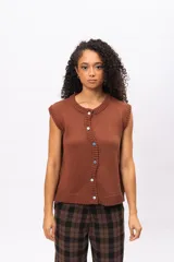 Chaleco de punto color marrón, sin mangas, con cuello redondo y cierre frontal asimétrico con botones. Presenta un diseño tejido con textura acanalada en los bordes.