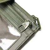 Billetera XL modelo Sasha, confeccionada en material símil cuero con textura granulada en color verde oliva. Presenta un cierre principal con solapa y broche a presión decorado con una flor metálica, además de un compartimento superior con cierre. Incluye el logo de la marca en metal en el frente.