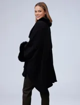 Ruana de tejido soft color negro, con cuello y puños decorados con apliques de piel sintética. Presenta un diseño abierto y holgado con caída fluida.